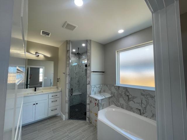 bathroom featuring vanity and plus walk in shower