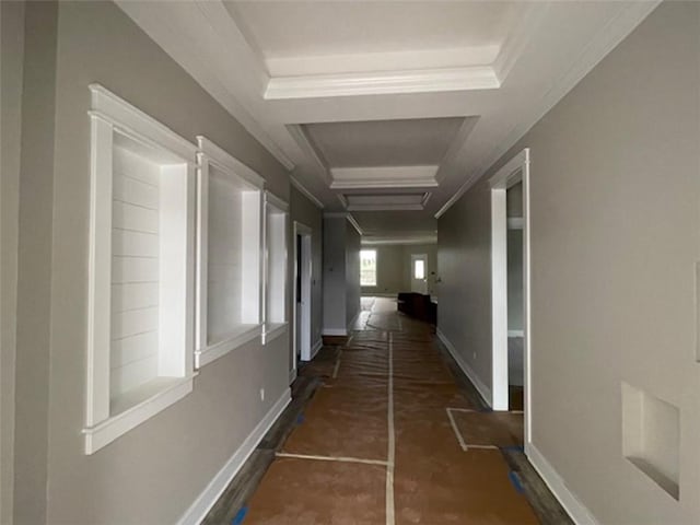 hallway with a raised ceiling and ornamental molding