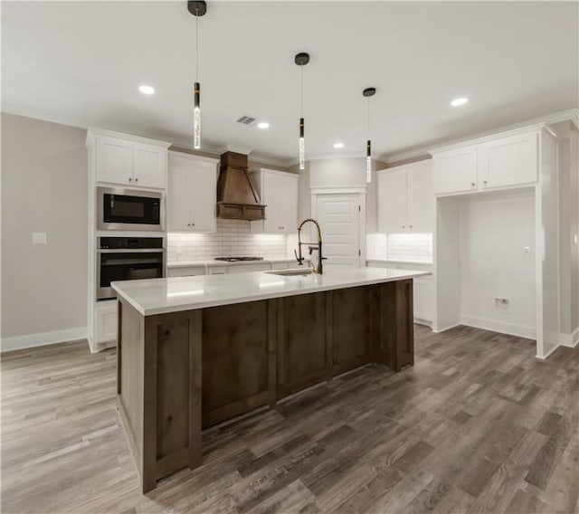 2908 Goldberg Dr, Bryan, TX 77808 - kitchen featuring stainless steel oven, premium range hood, a sink, built in microwave, and white cabinetry