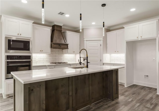 2908 Goldberg Dr, Bryan, TX 77808 - kitchen with stainless steel oven, custom range hood, black microwave, a sink, and white cabinets