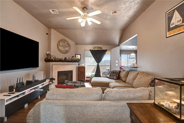 living room featuring a tile fireplace, dark hardwood / wood-style flooring, vaulted ceiling, and ceiling fan