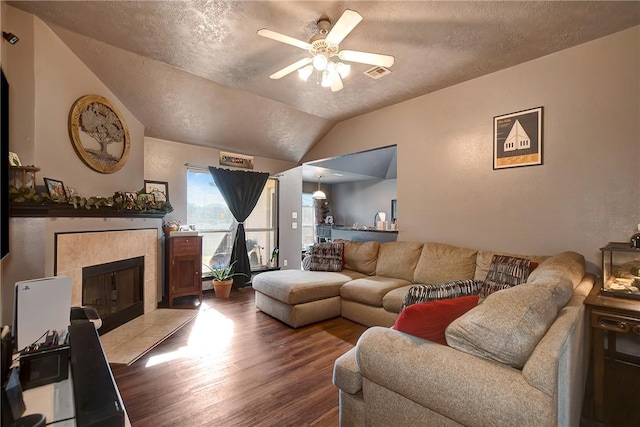 living room featuring a tile fireplace, hardwood / wood-style flooring, ceiling fan, and lofted ceiling