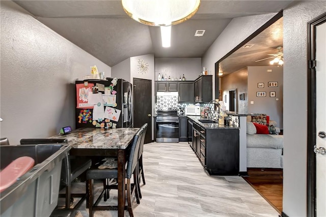 kitchen featuring decorative backsplash, dark stone counters, lofted ceiling, and appliances with stainless steel finishes