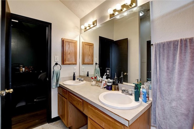 bathroom with tile patterned flooring, vanity, and vaulted ceiling