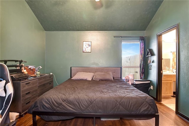 bedroom with ensuite bathroom, lofted ceiling, and light hardwood / wood-style floors