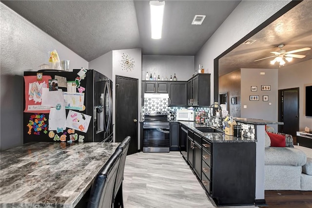 kitchen featuring kitchen peninsula, dark stone counters, ceiling fan, sink, and range