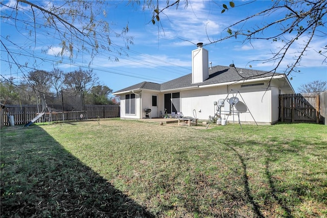 rear view of property with a lawn, a patio area, and a trampoline