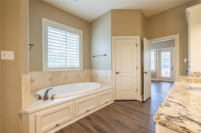 bathroom featuring vanity, a bath, and wood finished floors