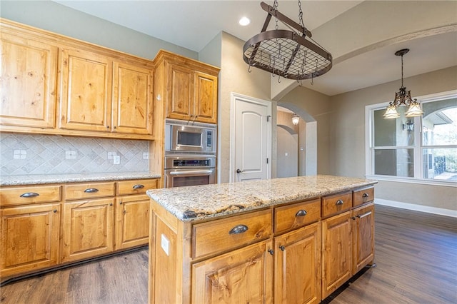 kitchen with decorative backsplash, arched walkways, appliances with stainless steel finishes, and dark wood-style floors