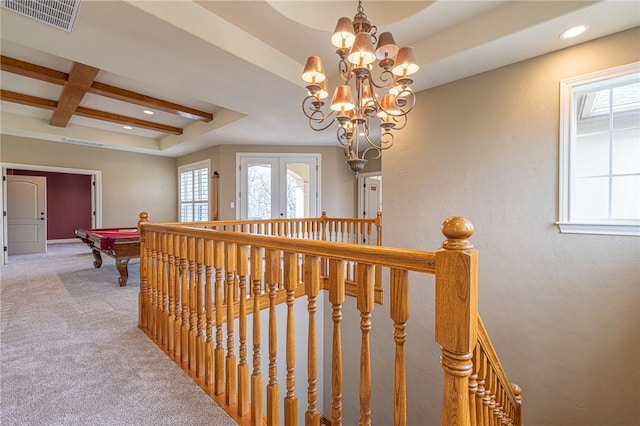 hallway with visible vents, an upstairs landing, coffered ceiling, and light carpet