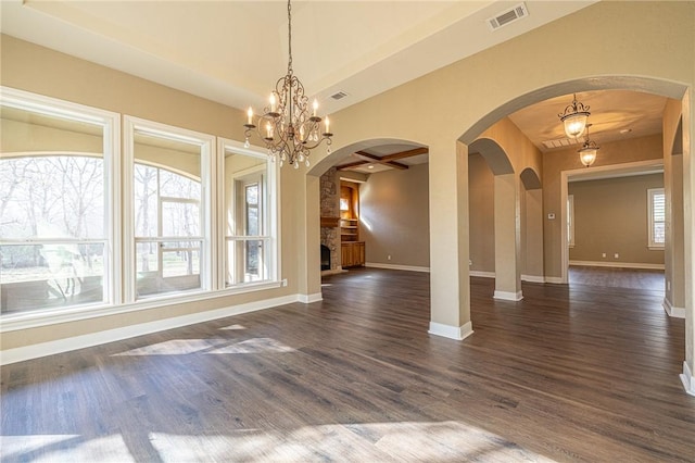 unfurnished room with baseboards, visible vents, arched walkways, dark wood-type flooring, and a notable chandelier