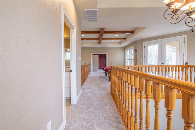 corridor with visible vents, beamed ceiling, light carpet, an inviting chandelier, and coffered ceiling