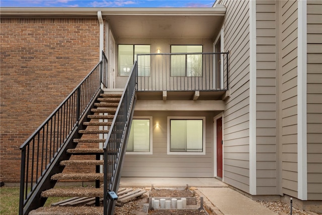 back of house featuring brick siding and stairs