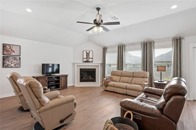 living room featuring ceiling fan, a fireplace, vaulted ceiling, and light hardwood / wood-style flooring