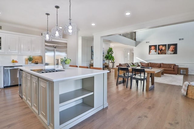 kitchen featuring white cabinetry, stainless steel appliances, a kitchen island, decorative light fixtures, and ornamental molding