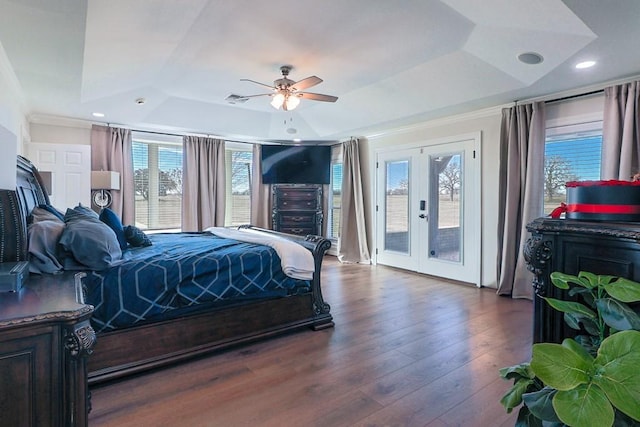 bedroom featuring ceiling fan, dark hardwood / wood-style floors, access to outside, a tray ceiling, and multiple windows