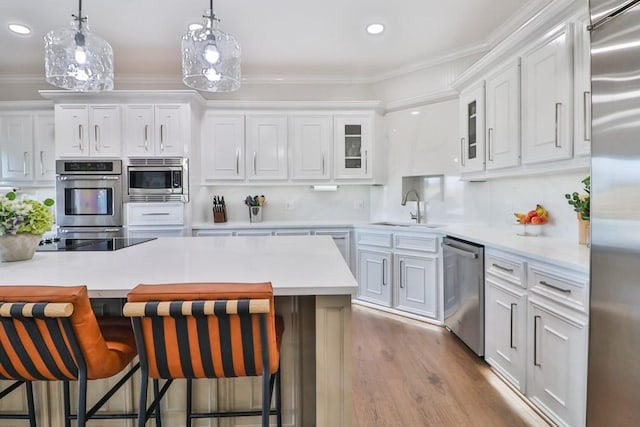 kitchen featuring appliances with stainless steel finishes, white cabinets, a breakfast bar, and sink