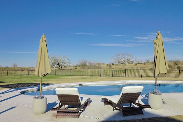 view of swimming pool featuring a yard, a rural view, and a patio