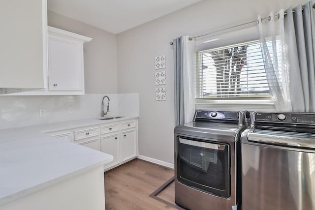 washroom featuring cabinets, light hardwood / wood-style floors, washing machine and clothes dryer, and sink