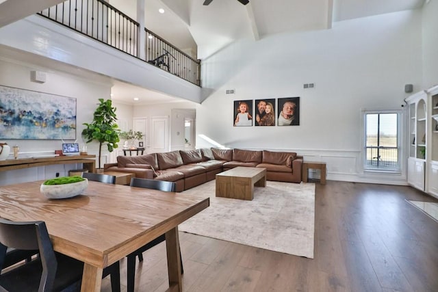 living room featuring a towering ceiling, ceiling fan, dark hardwood / wood-style floors, and beamed ceiling