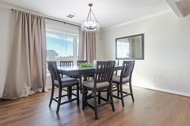 dining room featuring a healthy amount of sunlight, a notable chandelier, crown molding, and hardwood / wood-style floors