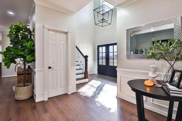 entrance foyer featuring french doors, dark wood-type flooring, an inviting chandelier, and ornamental molding