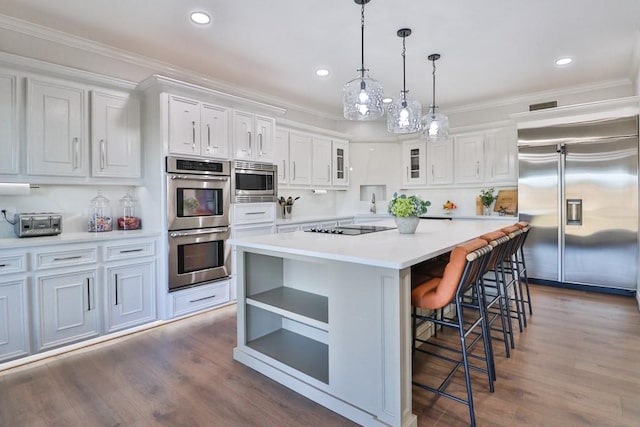 kitchen with white cabinetry, dark hardwood / wood-style floors, built in appliances, a kitchen island, and pendant lighting