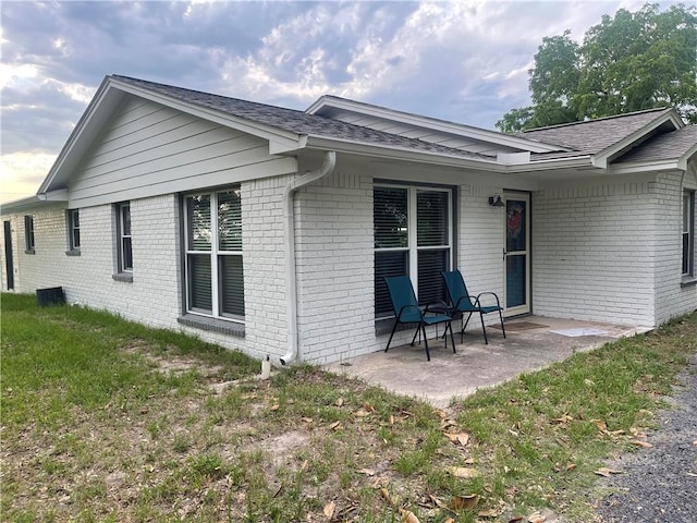 16659 Hwy 90 N, Bedias, TX 77831 - back of property featuring brick siding, roof with shingles, and a patio