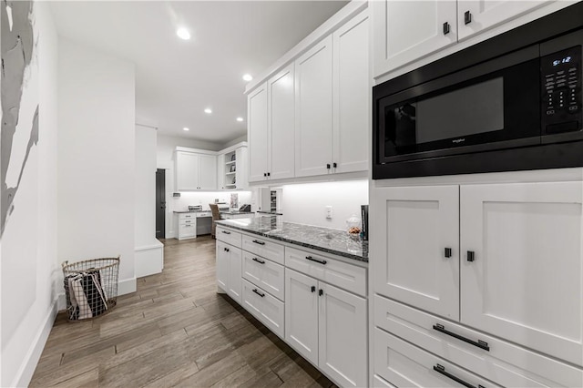 kitchen featuring recessed lighting, wood finished floors, white cabinets, dark stone counters, and black appliances