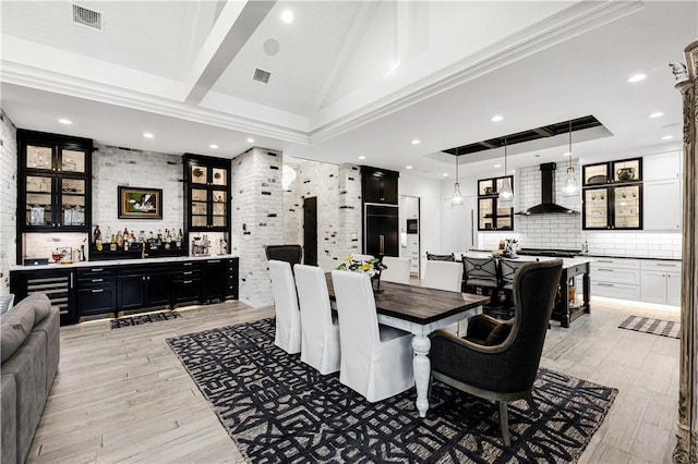 dining area featuring high vaulted ceiling, light wood finished floors, bar area, and visible vents