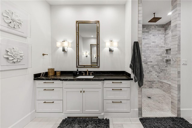 full bath featuring tile patterned flooring, baseboards, a walk in shower, and vanity