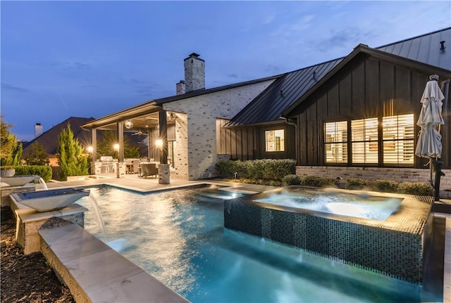 pool at dusk with a patio area, ceiling fan, an outdoor pool, and an in ground hot tub