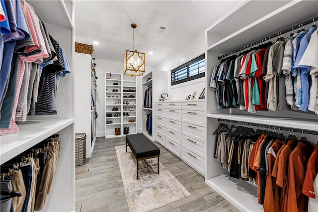 walk in closet with visible vents, a notable chandelier, and light wood finished floors