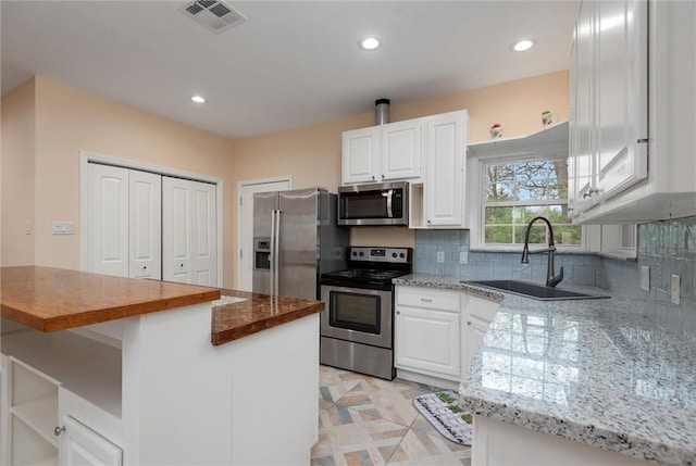 kitchen featuring tasteful backsplash, a sink, visible vents, white cabinets, and appliances with stainless steel finishes