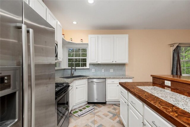 kitchen with stainless steel appliances, recessed lighting, white cabinetry, a sink, and backsplash
