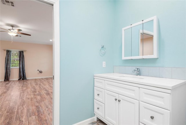 bathroom featuring vanity, baseboards, ceiling fan, visible vents, and wood finished floors