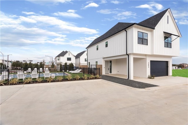 view of home's exterior featuring fence, a shingled roof, board and batten siding, an attached garage, and driveway
