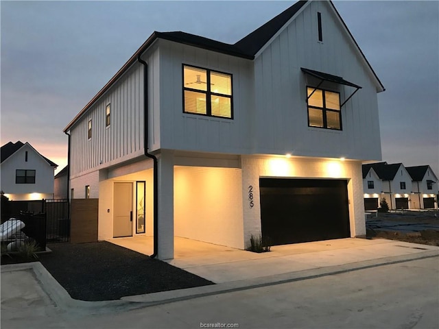 modern inspired farmhouse with a garage, fence, board and batten siding, and concrete driveway