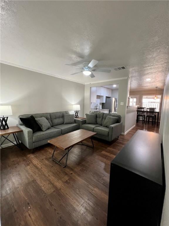 living room with dark hardwood / wood-style flooring, a textured ceiling, ceiling fan, and crown molding