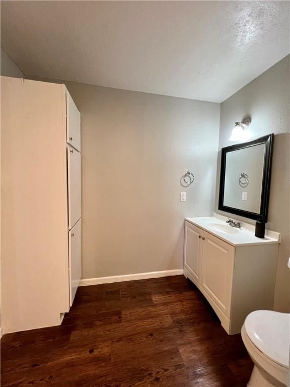 bathroom with toilet, wood-type flooring, and vanity