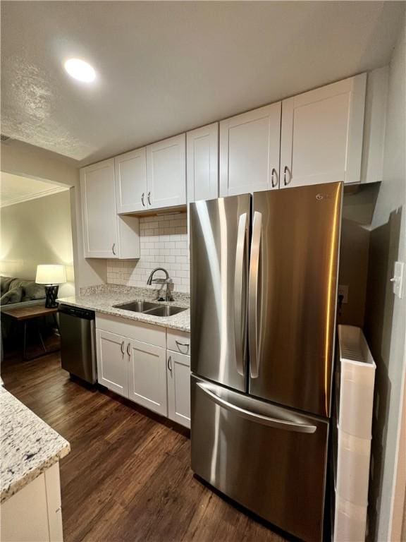 kitchen featuring appliances with stainless steel finishes, light stone counters, dark hardwood / wood-style floors, sink, and white cabinetry