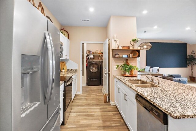 kitchen featuring appliances with stainless steel finishes, sink, white cabinets, washer / dryer, and hanging light fixtures