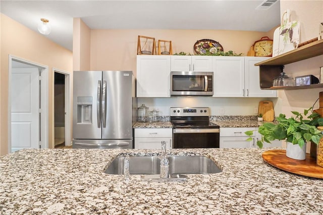 kitchen with white cabinetry, sink, stainless steel appliances, and light stone counters