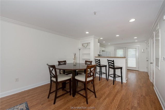 dining room with crown molding and hardwood / wood-style flooring