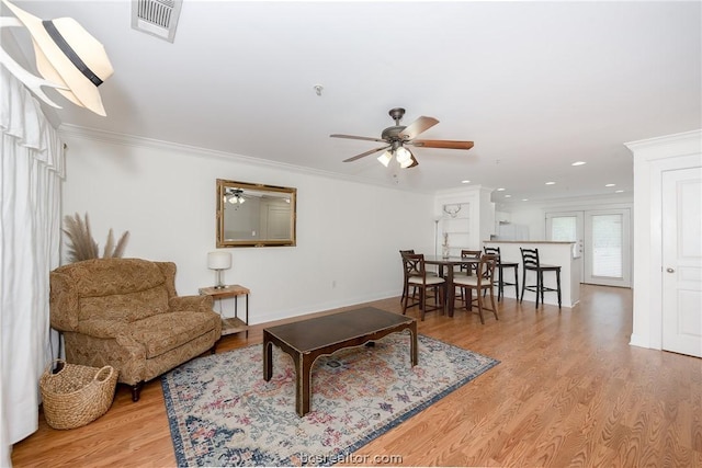 living room featuring light hardwood / wood-style flooring, ceiling fan, and crown molding