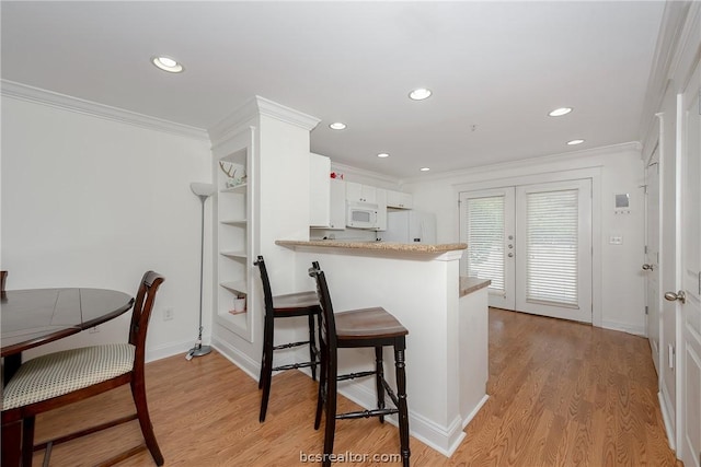 kitchen with white appliances, crown molding, white cabinetry, light hardwood / wood-style floors, and kitchen peninsula