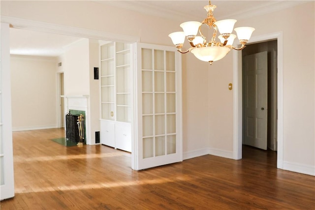 spare room with crown molding, dark hardwood / wood-style floors, and an inviting chandelier