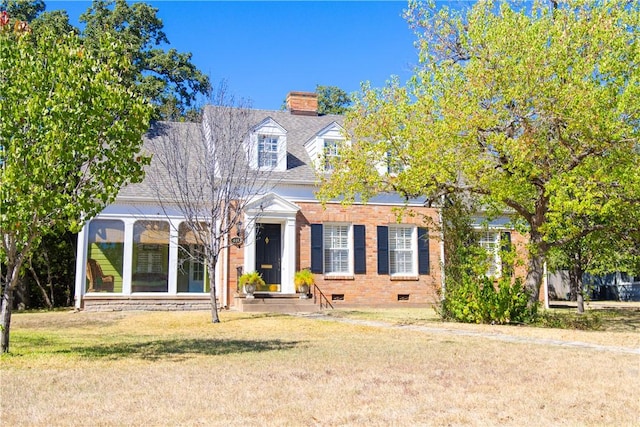 new england style home with a sunroom and a front lawn