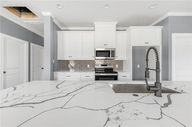 611 Levy St, Navasota, TX 77868 - kitchen with appliances with stainless steel finishes, a sink, white cabinetry, backsplash, and ornamental molding