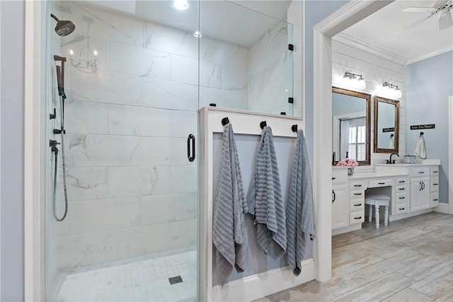 bathroom featuring a shower with door, vanity, ornamental molding, and ceiling fan